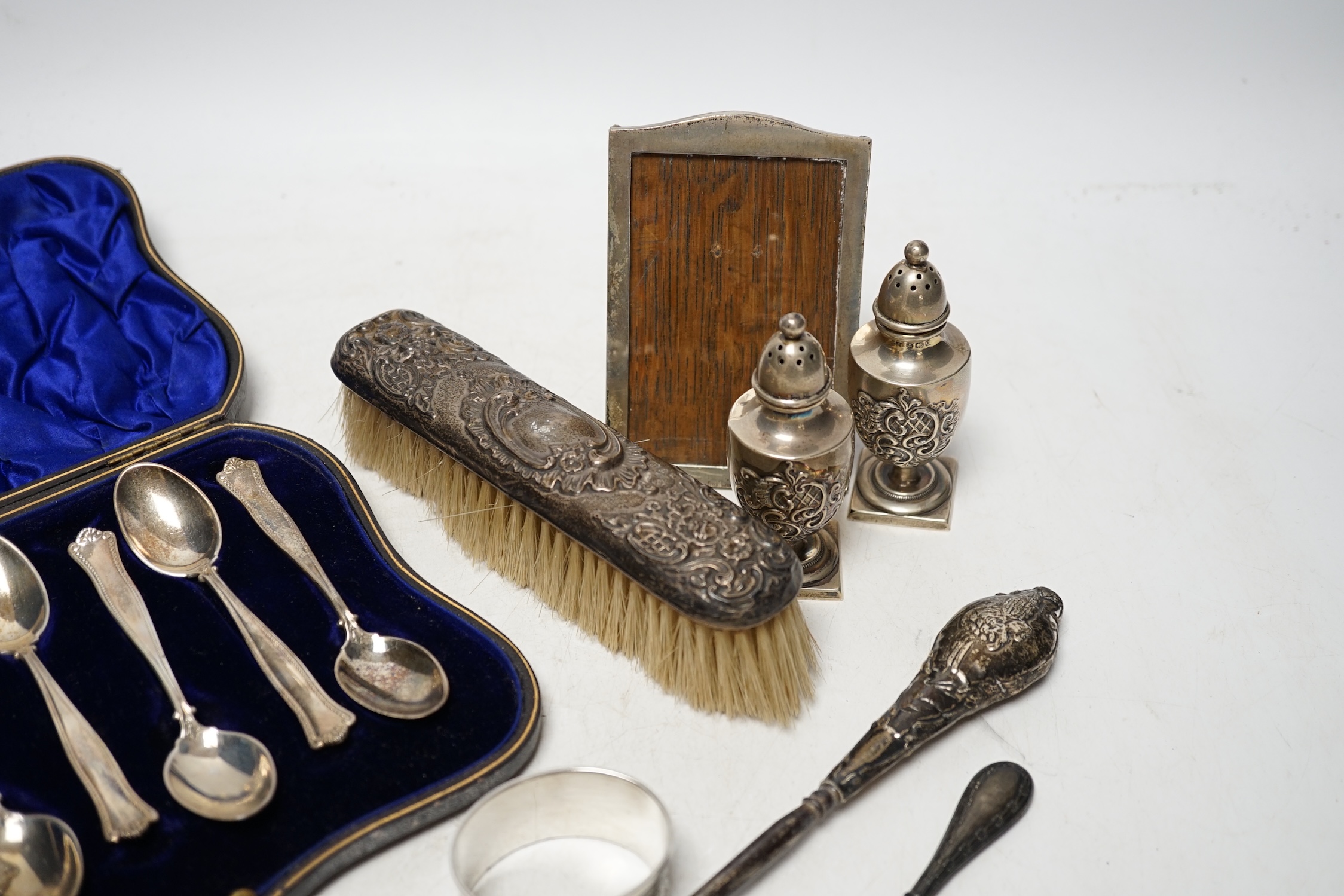 A cased set of six silver teaspoons, a pair of silver pepperettes and four other items including a photograph frame. Condition - poor to fair